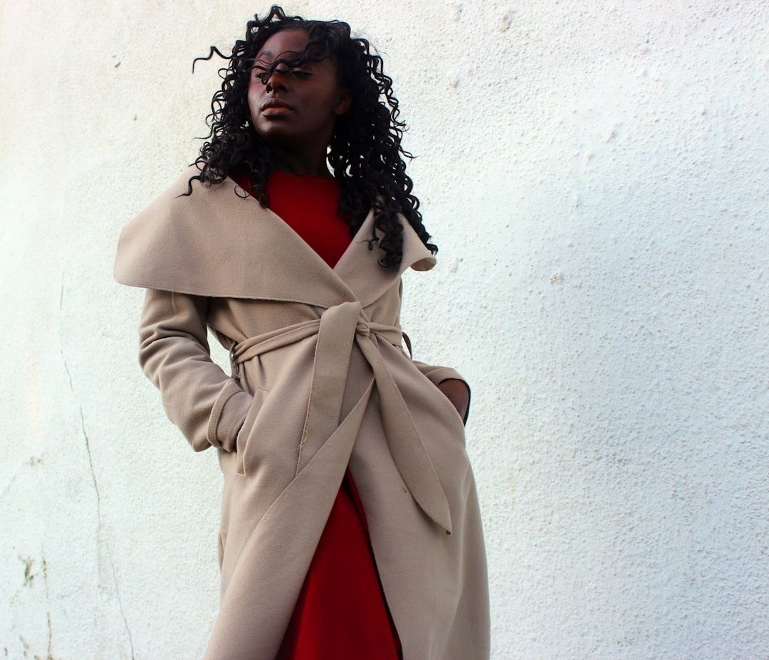 Person wearing a belted beige coat over a vivid red outfit