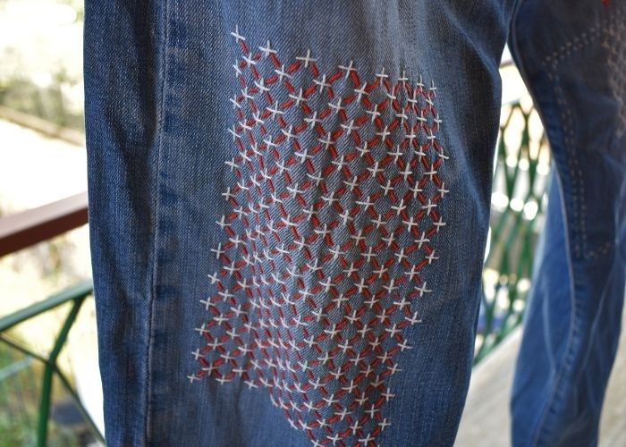 Close-up of denim repaired with dense red and white sashiko stitches