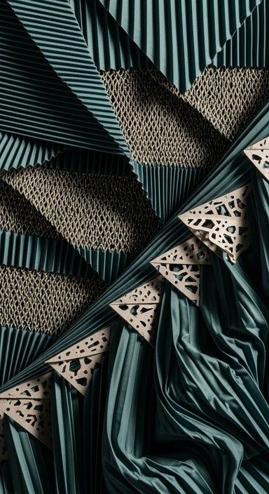 Sculptural teal pleats layered with honeycomb-textured fabric and cutouts